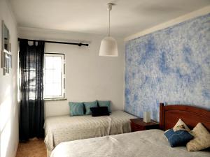 a bedroom with two beds and a blue wall at Casa Lagoa Mar in Costa de Santo André