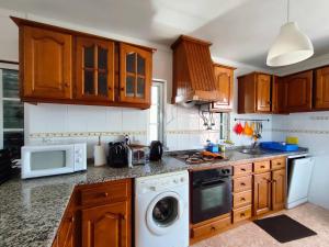 a kitchen with wooden cabinets and a washer and dryer at Casa Lagoa Mar in Costa de Santo André
