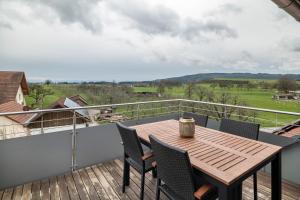 a deck with a wooden table and chairs on a balcony at Blick zum Säntis in Horgenzell