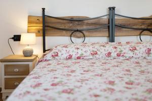 a bed with a red floral bedspread and a lamp at Timo in Pompeiana