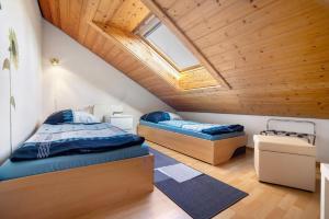 two beds in a room with a wooden ceiling at Ferienwohnung Tannhausen in Aulendorf