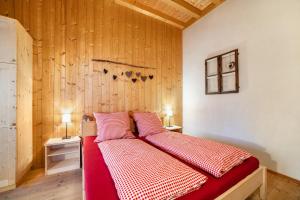 a bedroom with a bed with red and white sheets at Grushof App Paföl in Sluderno