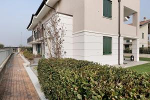 a white building with a brick sidewalk next to a bush at Condo-Micio Luna in Villafranca di Verona