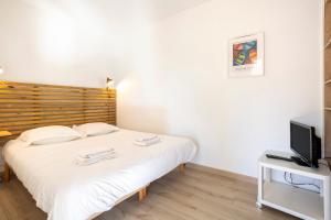a bedroom with a white bed and a television at La Cabane in Combrit