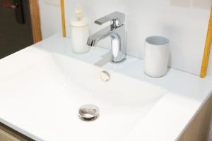 a bathroom sink with a faucet and two cups on it at La Cabane in Combrit +12 photos