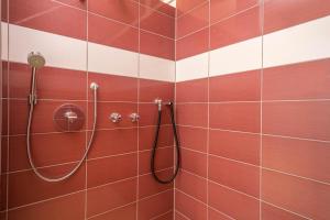a shower in a bathroom with red and white tiles at Heimelig im Hirschen App 118 in Schönwald +14 photos