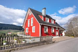 a red house with a fence in front of it at Villa Pauline in Baiersbronn
