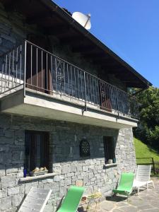 ein Steingebäude mit 2 Stühlen und einem Balkon in der Unterkunft Casa delle Befane in Aurigeno