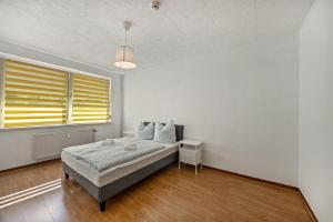 a white bedroom with a bed and a window at Wohnung am Geiseltalsee in Mücheln