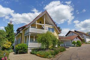 a yellow house with a white balcony on a street at Ferienwohnungen Hog , Ringsheim in Ringsheim