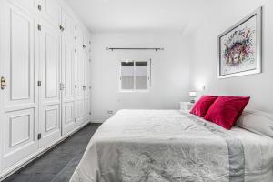 a white bedroom with a large bed with red pillows at Bright in Agaete