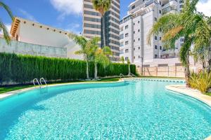 a swimming pool with palm trees and buildings at Infinium 12b in Calpe