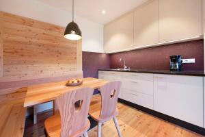 a kitchen with a wooden table and two chairs at Teutenhofer Zwetschge in Feldthurns +11 photos