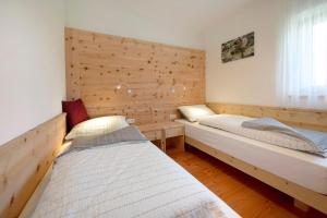 a bedroom with two beds and a wooden wall at Teutenhofer Zwetschge in Feldthurns