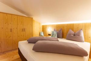 two beds in a room with wood paneling at Daimlhof Ferienwohnung Moosherz in Völs am Schlern