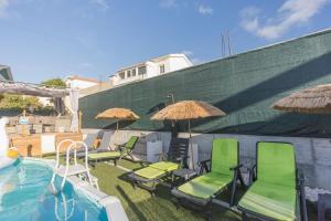 a group of chairs and umbrellas next to a pool at Refúgio Das Barcas in Lourinhã