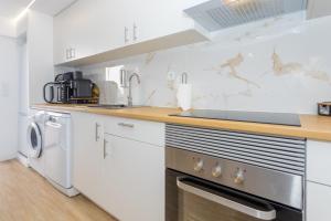 a kitchen with white cabinets and a stove top oven at Refúgio Das Barcas in Lourinhã