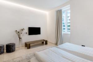a white bedroom with a bed and a tv at App 103 Palazzo Cavour in Bolzano