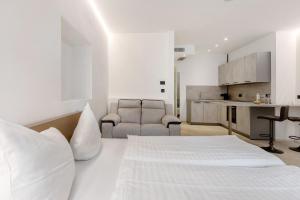 a white bedroom with a bed and a kitchen at App 103 Palazzo Cavour in Bolzano