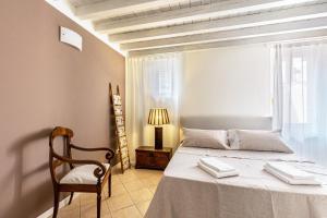 a bedroom with a bed and a chair and a window at Nido di Cisano in San Felice del Benaco +15 photos