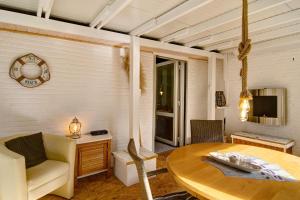 a living room with a table and a chair and a television at Ferienhaus Piet in Berumbur