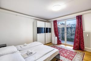 a bedroom with two beds and a large window at Aldars Urban Trio Suite No.6 in Munich
