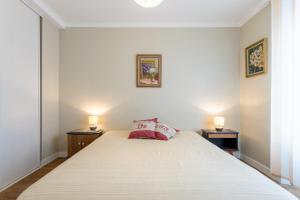 a bedroom with a large white bed with two lamps at Appartement face Mer - 50m plage in Douarnenez