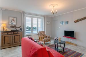a living room with a red couch and a tv at Appartement face Mer - 50m plage in Douarnenez