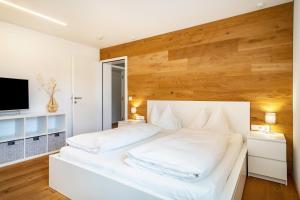 a bedroom with a white bed with a wooden wall at Ferienwohnung Lauterach in Lauterach