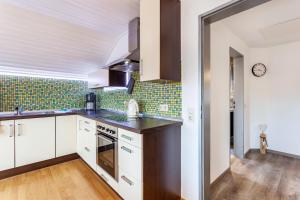 a kitchen with white cabinets and green tiles at Lydias Ferienwohnung in Schmallenberg +13 photos