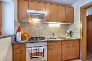 a kitchen with wooden cabinets and a stove and a sink at Wohnung Arnika Stücklhof in San Genesio Atesino
