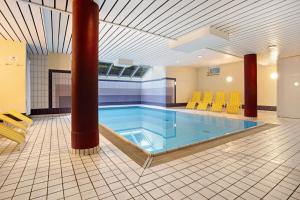 a swimming pool in a room with yellow chairs at Haus A Cappella B6 in Binz