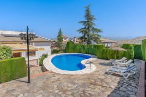 a swimming pool in a yard with a bench and umbrella at Villa Leonor con piscina privada in Monachil