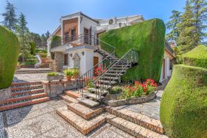 a house with a staircase and some green hedges at Villa Leonor con piscina privada in Monachil
