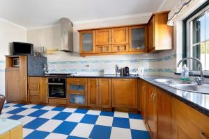 a kitchen with wooden cabinets and a checkered floor at Villa Delphin in Lagos