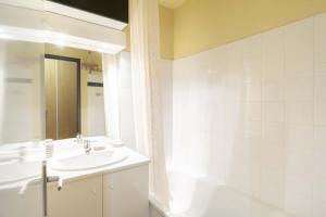 a white bathroom with a sink and a shower at Appart valfrejus in Modane +14 photos