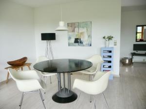 a dining room with a black table and white chairs at Haus am See in Illmensee