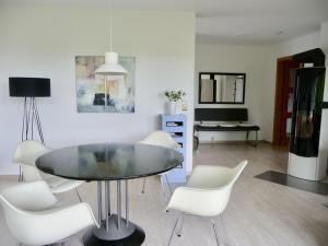 a dining room with a glass table and white chairs at Haus am See in Illmensee