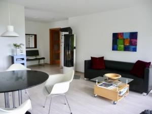 a living room with a black couch and a table and chairs at Haus am See in Illmensee