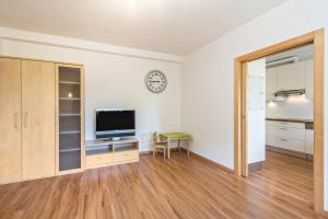 an empty living room with a television and a clock on the wall at Ferienwohnung Lafreid Algund in Lagundo