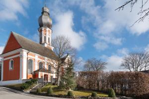 a red and white church with a clock tower at Modernes Apartment Ammersee in Windach