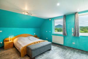 a blue bedroom with a bed and two windows at bei den Holzäppeln in Völkersweiler
