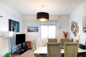 a living room with a table and chairs and a tv at Maison Cosy, Lac et Plages in Hossegor