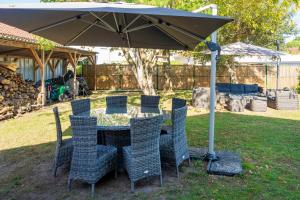 a table and chairs under an umbrella in a yard at Maison Cosy, Lac et Plages in Hossegor