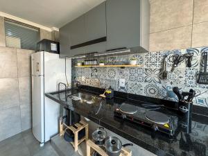 a kitchen with a black counter top and a refrigerator at Studio 43 - Central Coração de Franca in Franca