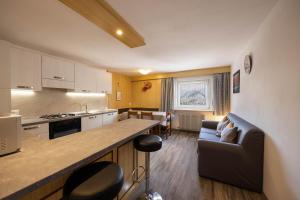 a kitchen and living room with a couch and a table at Appartamento Primavera 4 in Moena