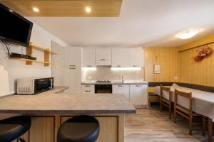 a kitchen with a counter and a table with chairs at Appartamento Primavera 4 in Moena +14 photos