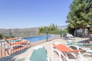 a pool with chaise lounge chairs and a swimming pool at Casa las Olivas in Sayalonga