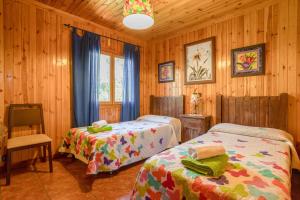 a bedroom with two beds in a room with wooden walls at Casa las Olivas in Sayalonga +17 photos