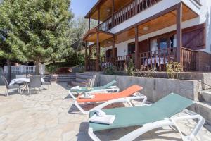 a group of lounge chairs and tables in front of a building at Casa las Olivas in Sayalonga